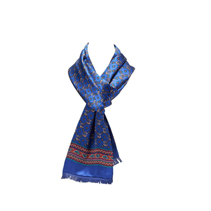 A SusanSilk Buckle Pattern Long Silk Brushed Scarf in blue, featuring a paisley design and decorative border, tied in a loose knot.