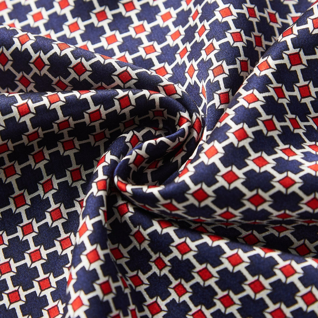 Close-up of the luxurious Cross Pattern Long Silk Brushed Scarf by SusanSilk, showcasing a geometric design in red, white, and blue with interlocking hexagonal shapes. The silk fabric is slightly gathered and twisted at the center.