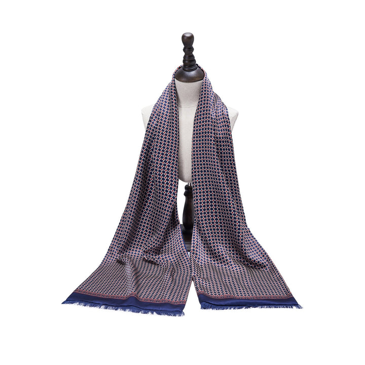 A mannequin showcases the Cross Pattern Long Silk Brushed Scarf with fringes at the ends, draped over its shoulders. This SusanSilk scarf features a blue geometric design on a lighter background.