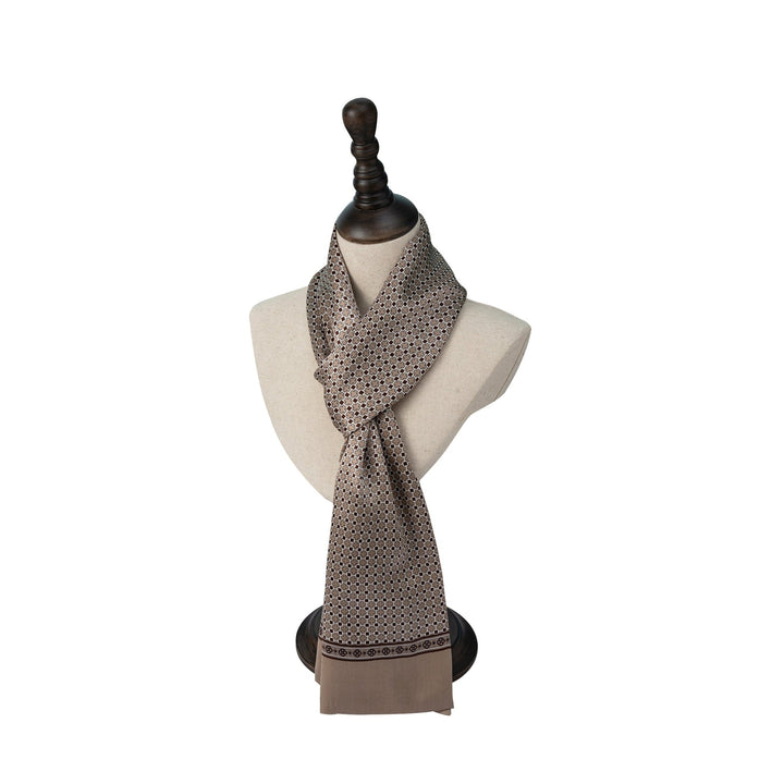 A beige and brown patterned Cross Pattern Long Silk Scarf by SusanSilk draped around a mannequin torso with a dark wooden stand.