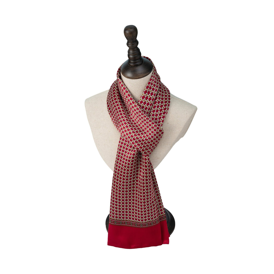 A Cross Pattern Long Silk Scarf by SusanSilk, featuring a red and gold design, elegantly draped on a white mannequin bust with a dark wooden stand.