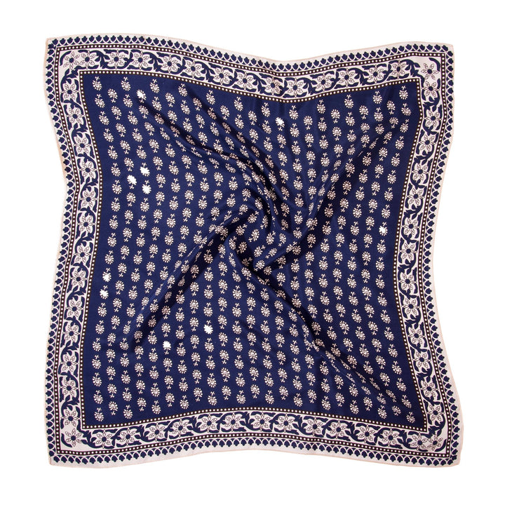 A Floral Pattern Square Silk Scarf by SusanSilk, featuring a blue background with a white floral pattern and bordered by larger floral designs, laid flat with slight wrinkles in the center.