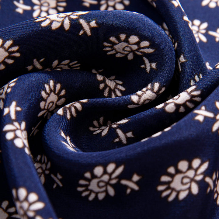 Close-up of a folded Floral Pattern Square Silk Scarf by SusanSilk, showcasing its dark blue silk fabric adorned with a white floral pattern.