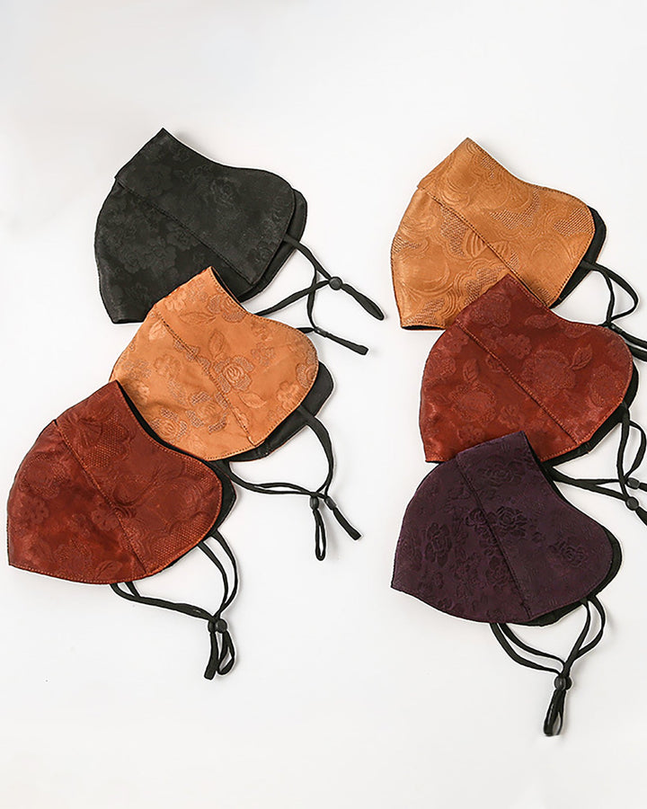 A set of six SusanSilk Jacquard Upturned Brim Hat & Face Masks, each in a different color and crafted from luxurious silk with black straps, is elegantly displayed on a white surface.