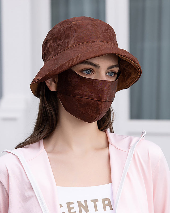 A person wearing a SusanSilk Jacquard Upturned Brim Hat & Face Mask, dressed in a silk pink jacket.