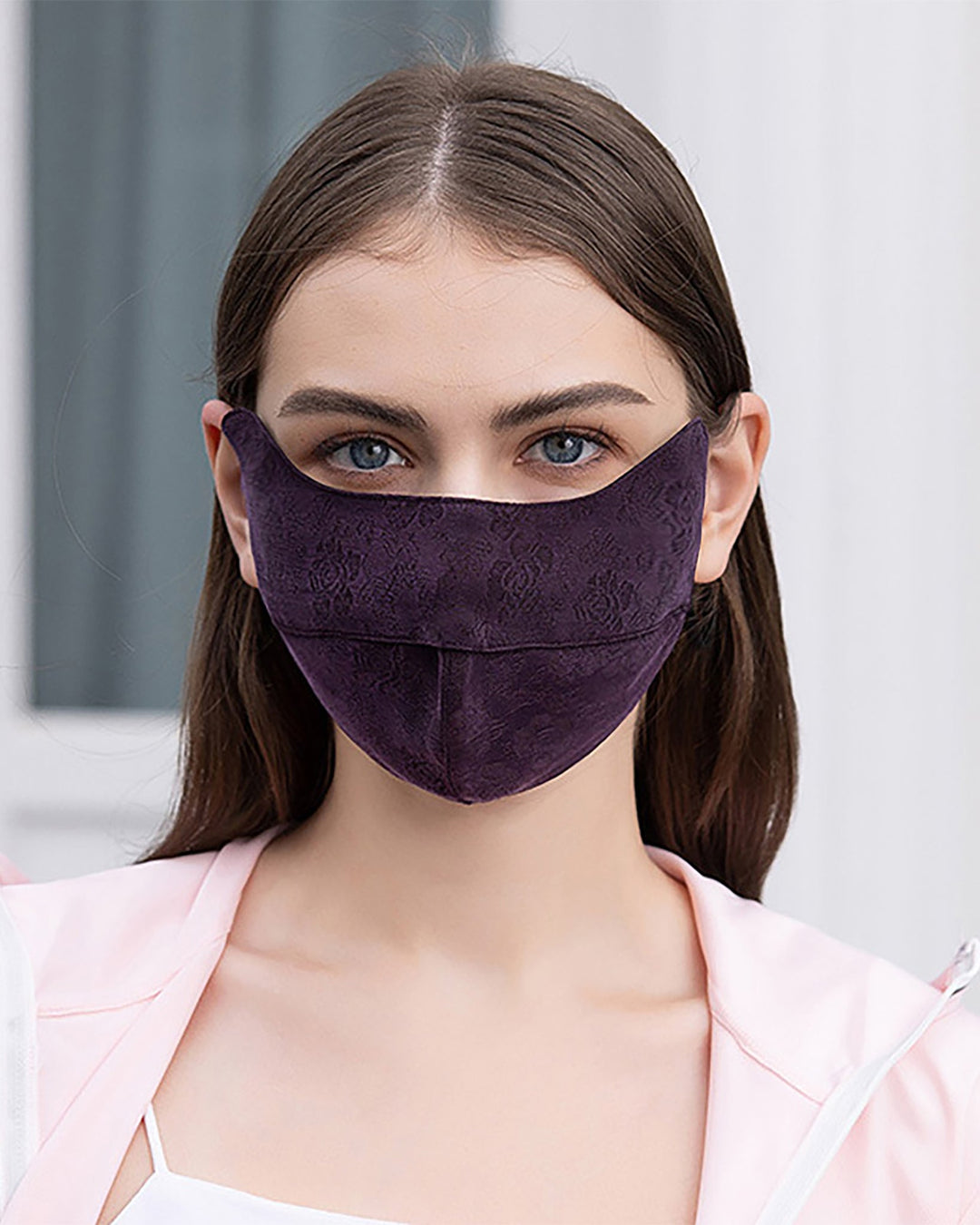 A woman wearing a dark purple Jacquard Upturned Brim Hat & Face Mask from SusanSilk and a light pink top looks directly at the camera. Her hair, resembling smooth SusanSilk, is parted in the middle and falls straight down her shoulders.