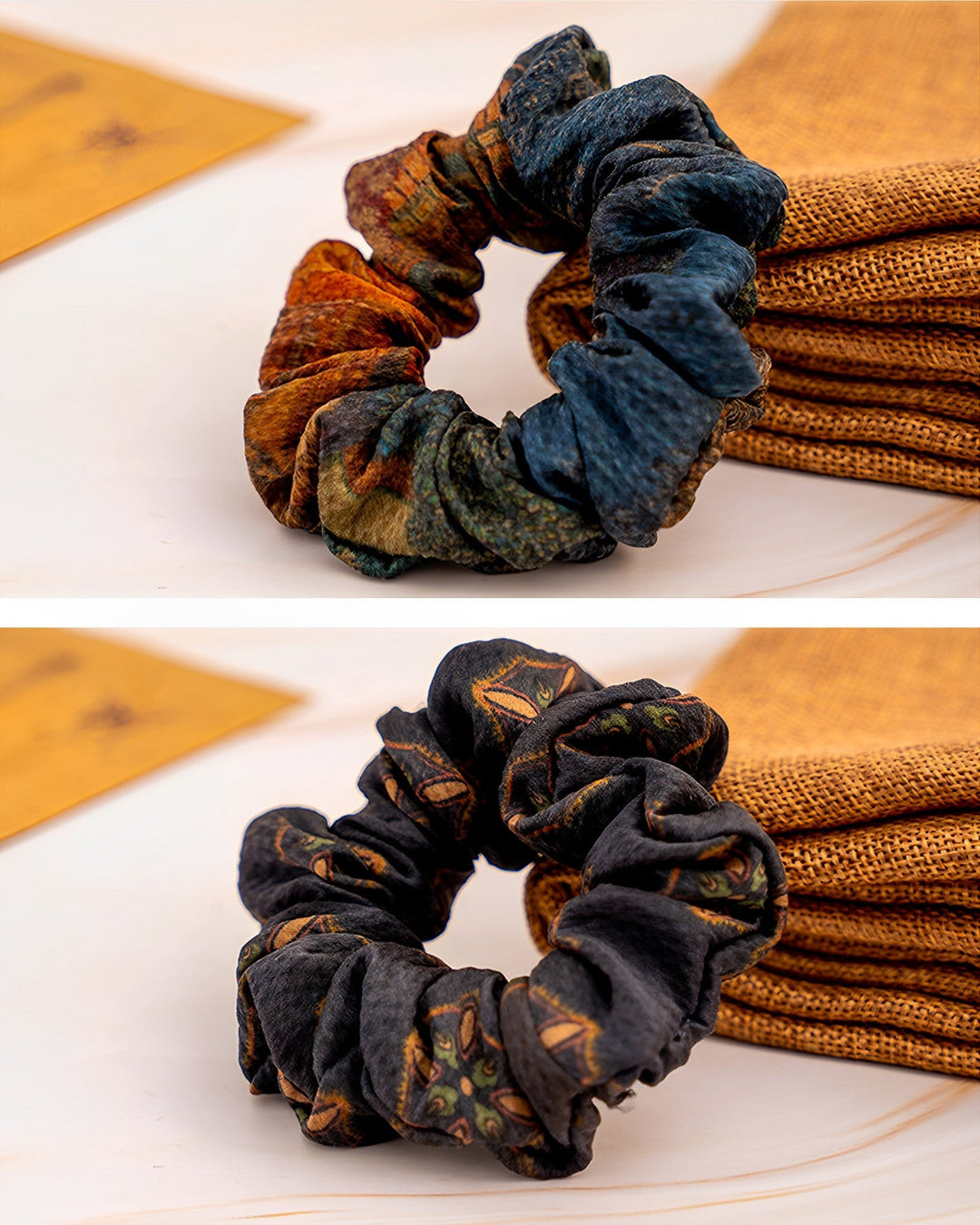 Two Gambiered Canton Gauze Silk Scrunchies, measuring 3cm and crafted by SusanSilk, are displayed on a white surface. The top scrunchie features an array of multi-colored shades of blue and brown, while the bottom one is black with a printed pattern.