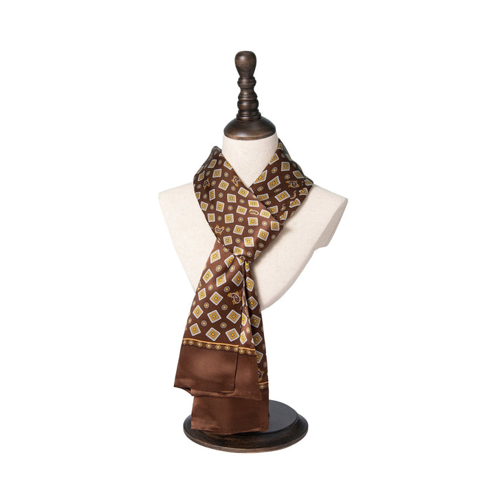 A SusanSilk Gemstone Long Silk Scarf with a brown geometric pattern elegantly displayed on a white mannequin bust with a dark wooden base and stand.