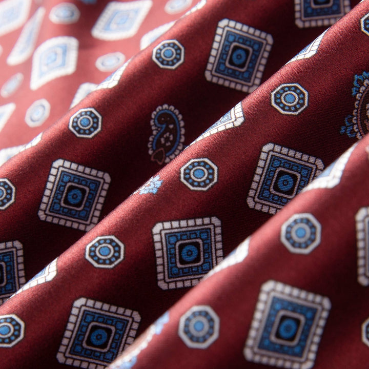 Close-up of the luxurious red Gemstone Long Silk Scarf from SusanSilk, featuring an intricate pattern of blue and white squares and paisleys.