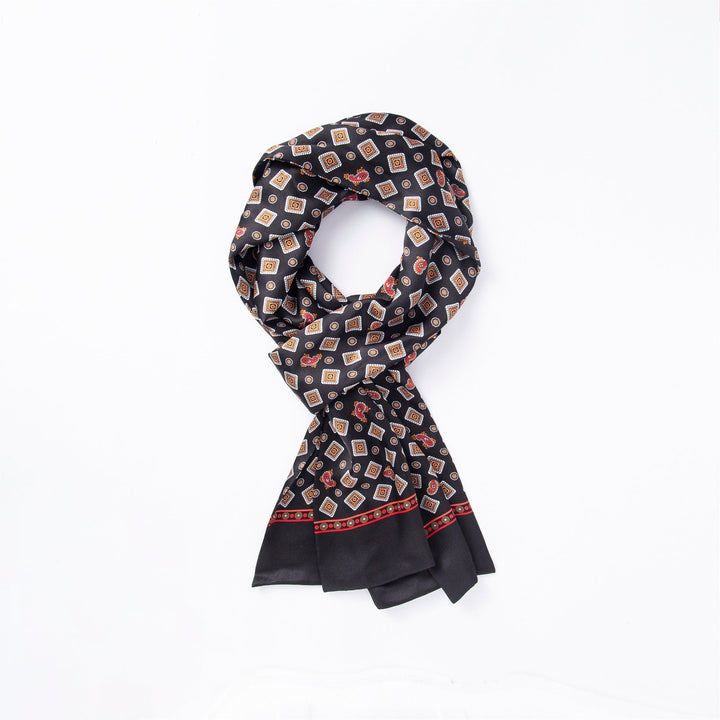 The Gemstone Long Silk Scarf from SusanSilk boasts a sophisticated black silk base adorned with a geometric pattern of small squares and diamonds in red, beige, and white. It features a striking red border along the edges and comes neatly folded, adding an elegant touch to any outfit.