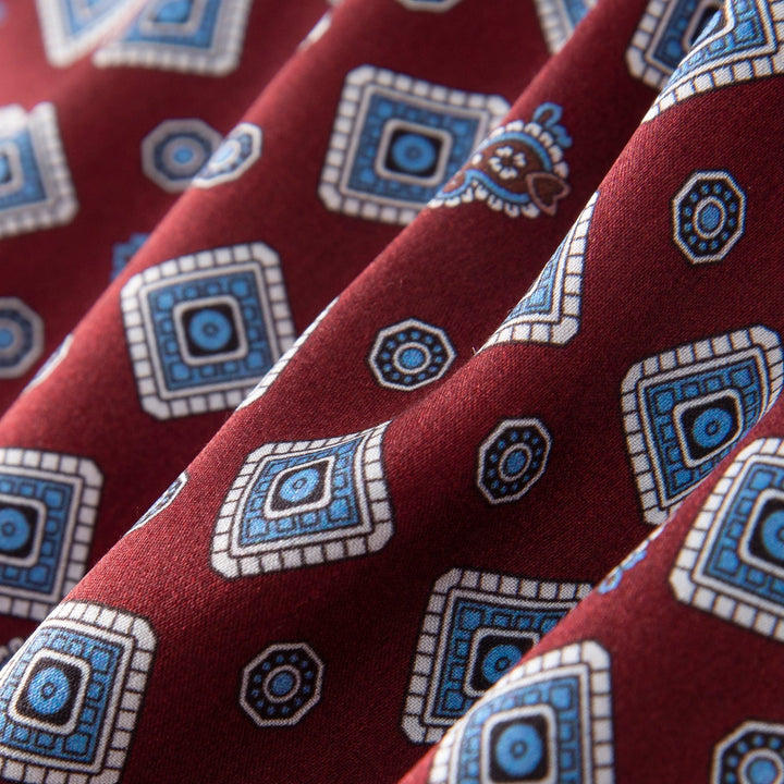 Close-up of the Gemstone Long Silk Scarf by SusanSilk, showcasing blue and white geometric designs on a burgundy background.