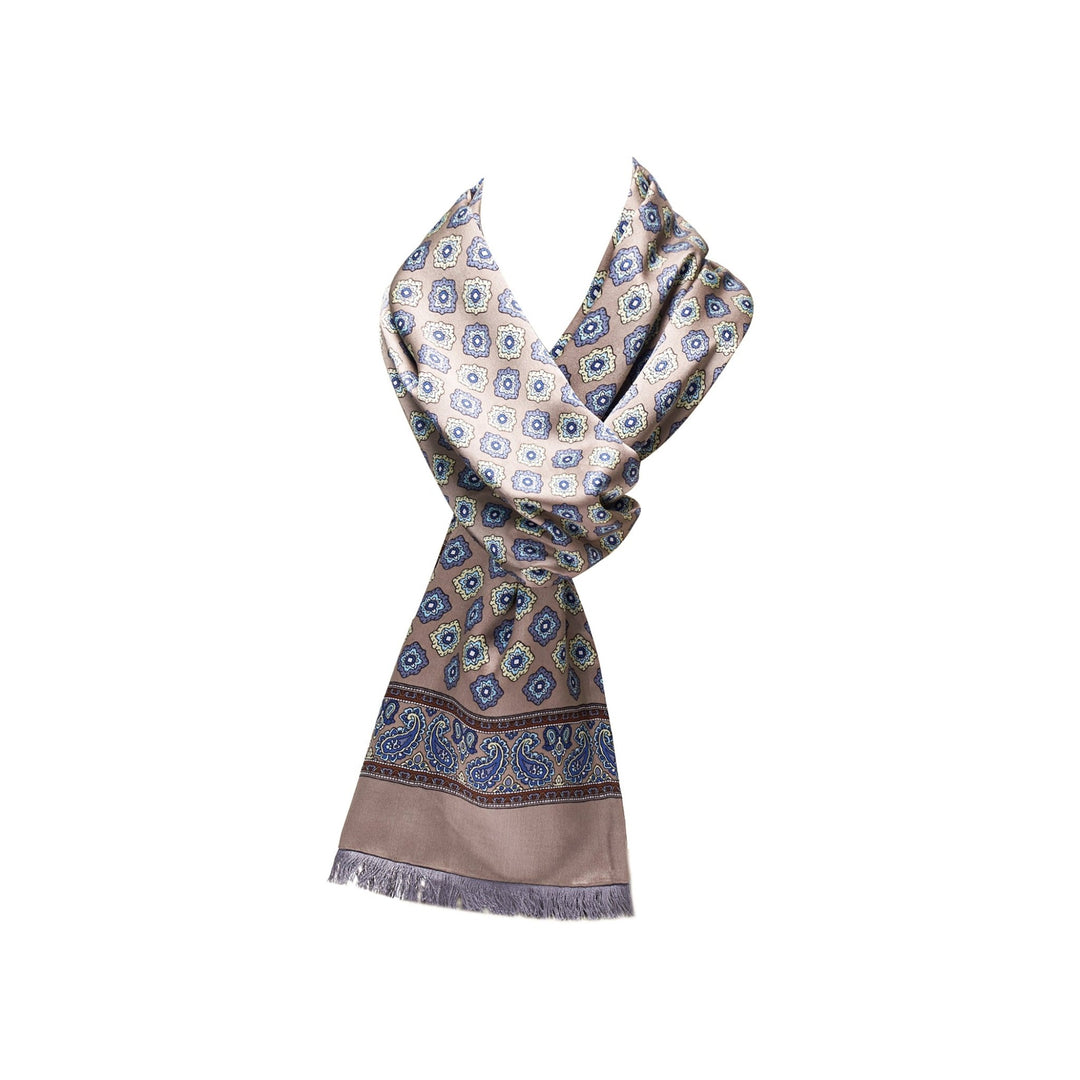 The Geometric Pattern Long Silk Brushed Scarf from SusanSilk in Ash-Gold showcases exquisite blue and beige designs, complete with fringed edges. This elegant silk scarf drapes beautifully.