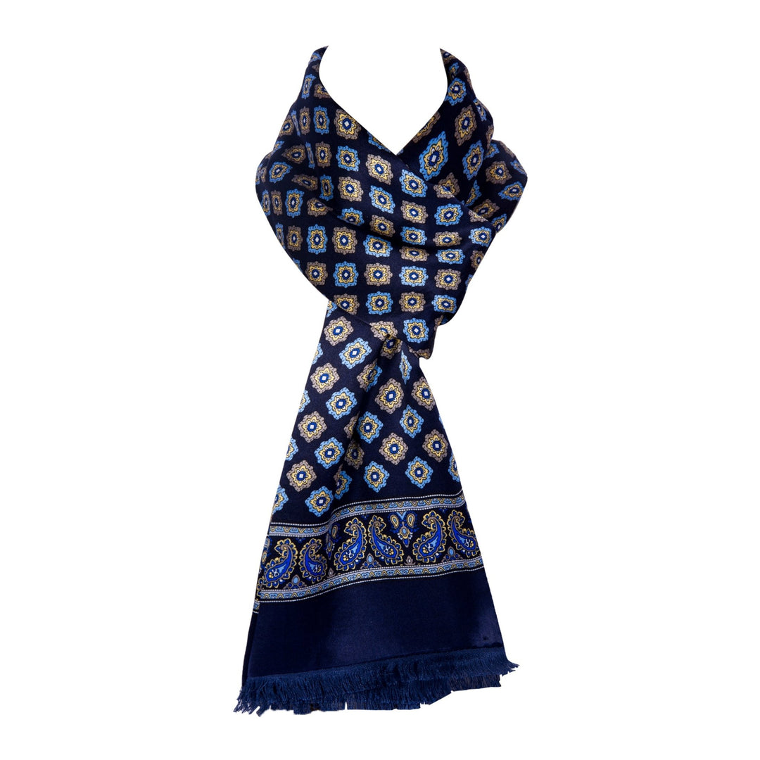 A Geometric Pattern Long Silk Brushed Scarf in dark blue from SusanSilk, featuring intricate geometric and paisley designs in shades of blue and white, complete with tassels at the ends.