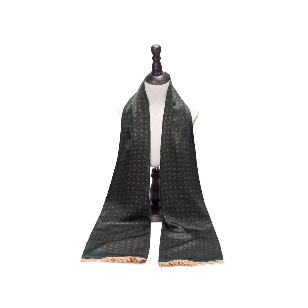 The Geometric Pattern Long Silk Brushed Scarf in green, a SusanSilk creation, is elegantly displayed on a white mannequin torso with a dark stand.