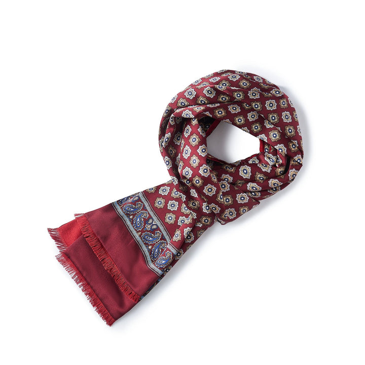 A neatly folded Geometric Pattern Long Silk Brushed Scarf in red from SusanSilk, adorned with a flower motif and a paisley design border, displayed on a white background.