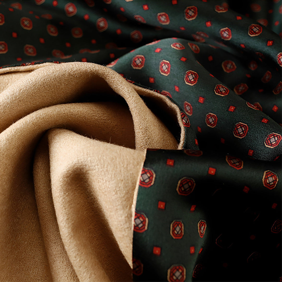 A close-up of two types of fabric: one is brown and suede-like, and the other is a dark green Geometric Series Long Silk Brushed Scarf by SusanSilk, featuring a red and brown geometric pattern.