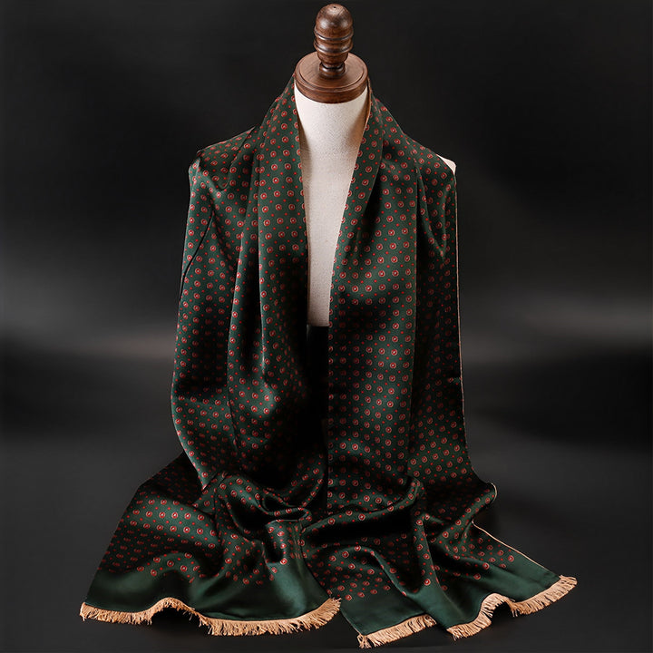 A SusanSilk mannequin with a wooden head displays the Geometric Series Long Silk Brushed Scarf, featuring a dark green background adorned with red polka dots and beige fringed edges.