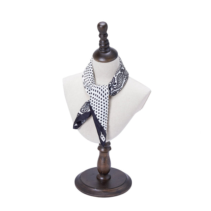 A Jigsaw Series Square Silk Scarf from SusanSilk, featuring a black and white pattern, is displayed on a dress form with a dark wooden base and stand.