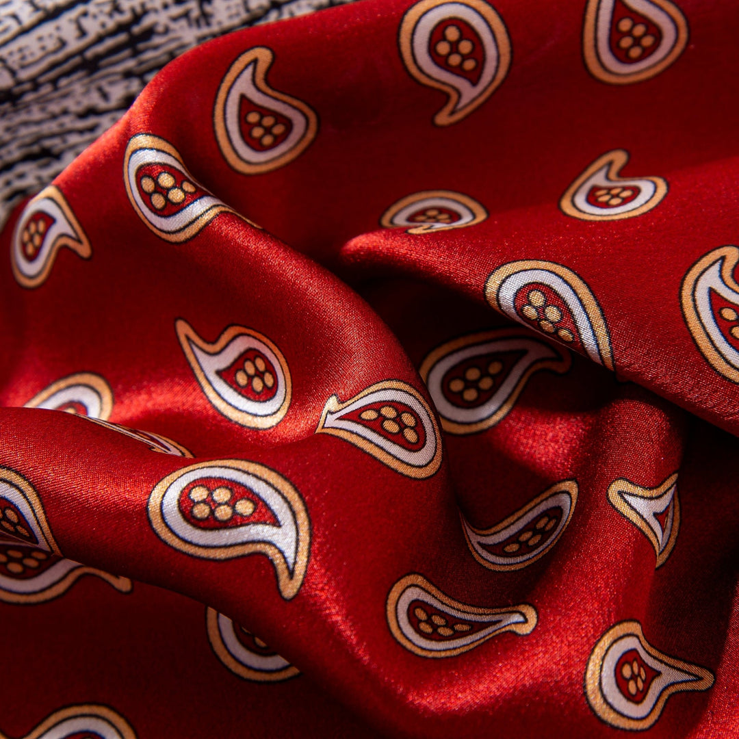 Close-up of a SusanSilk Jigsaw Series Square Silk Scarf showcasing rich red satin adorned with intricate paisley motifs in teardrop shapes, highlighted with elegant gold and white designs, capturing the essence of luxurious silk.