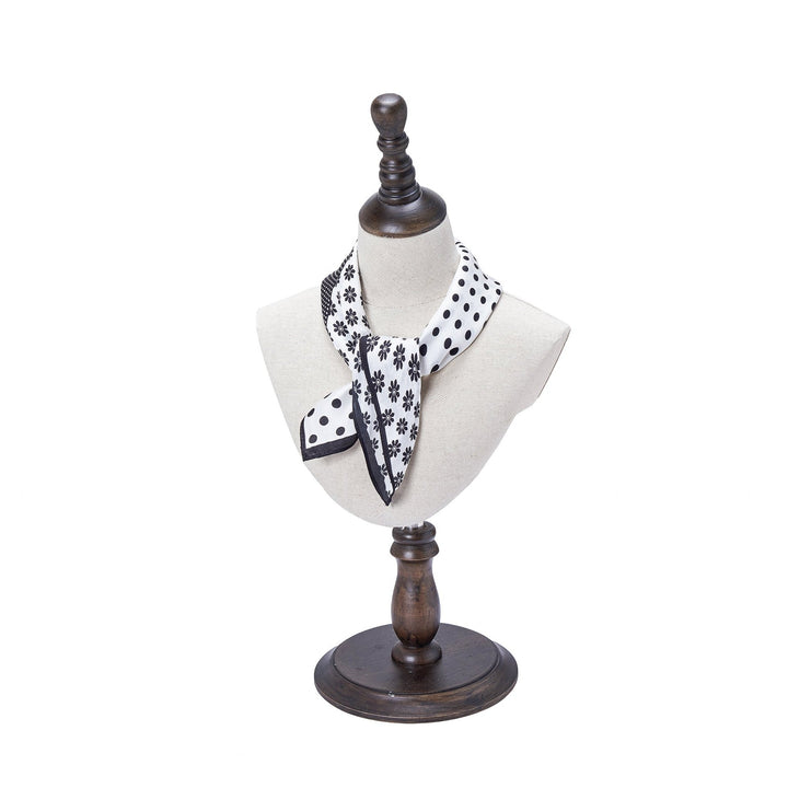 The SusanSilk Jigsaw Series Square Silk Scarf, featuring black polka dots and flower patterns, is displayed on a beige mannequin bust with a wooden stand.