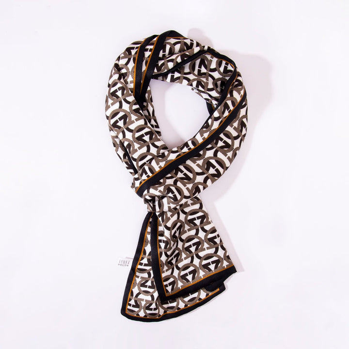 An Ohm Pattern Narrow Long Silk Scarf by SusanSilk, featuring a geometric black, white, and brown design, is draped neatly against a plain white background.