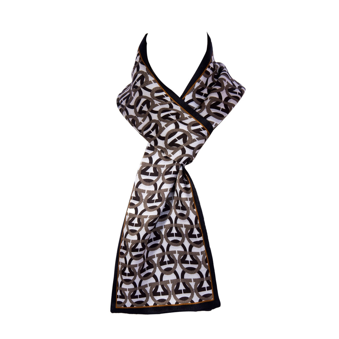 An Ohm Pattern Narrow Long Silk Scarf by SusanSilk, featuring a black, white, and gold pattern, draped and tied elegantly on a white mannequin.