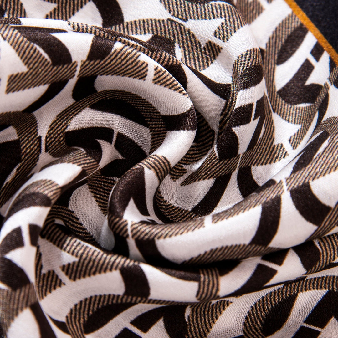 Close-up of the SusanSilk Ohm Pattern Narrow Long Silk Scarf, showcasing its black and white geometric design, with visible folds and a delicate texture.