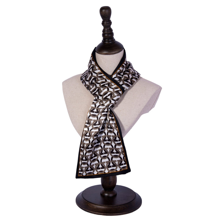 A mannequin displays the Ohm Pattern Narrow Long Silk Scarf by SusanSilk, featuring a geometric design in black, white, and brown. The silk scarf, knotted loosely around the neck, adds a touch of elegance.