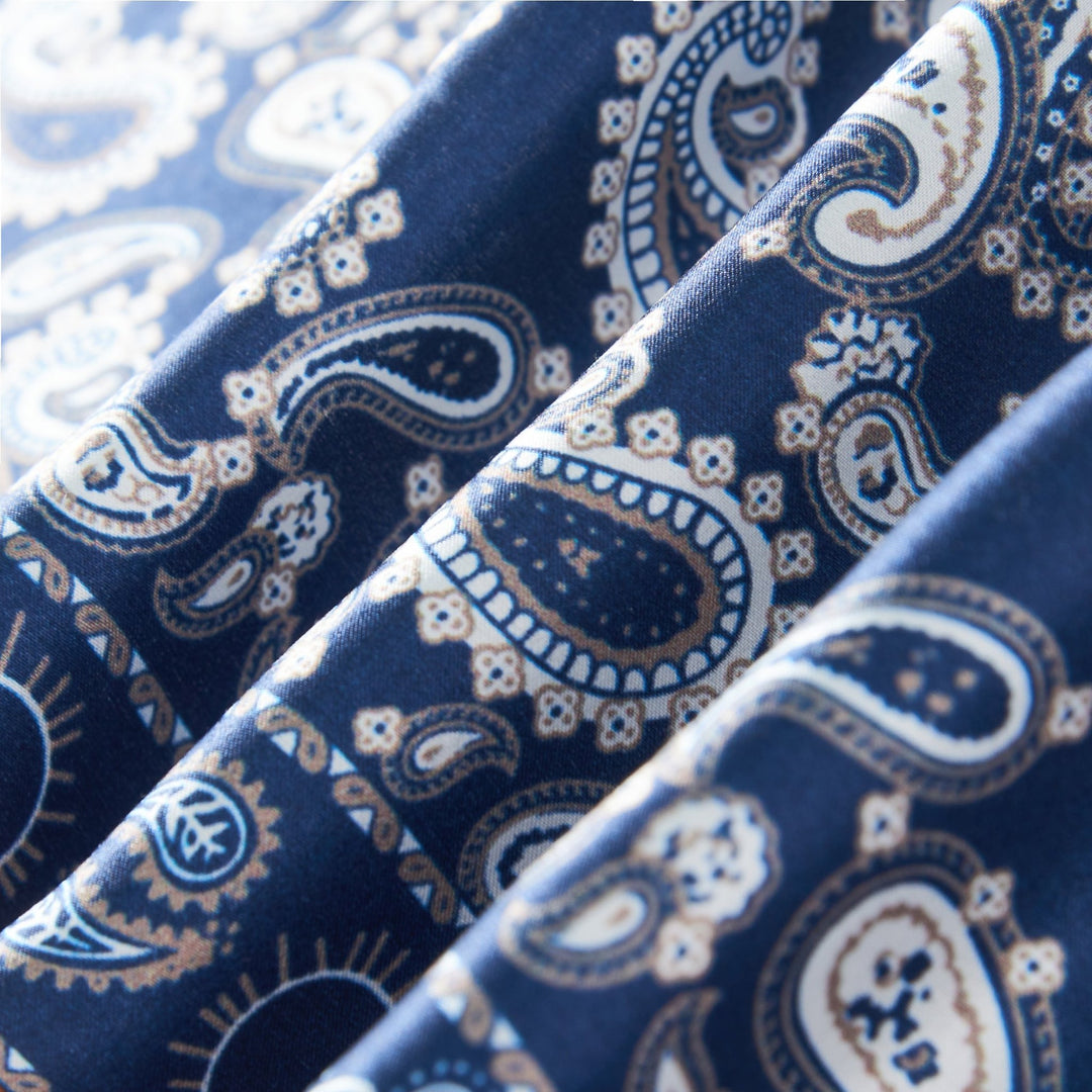 Close-up image of the Paisley Series Square Silk Scarf by SusanSilk, showcasing its blue silk fabric adorned with a white and light blue paisley pattern. The folds in the scarf create subtle shadows, emphasizing the intricate design.