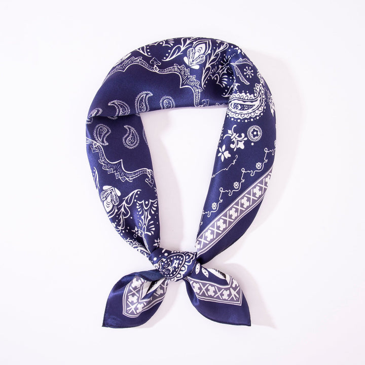 A Paisley Square Silk Scarf in navy and white by SusanSilk is neatly tied in a loop against a plain white background.