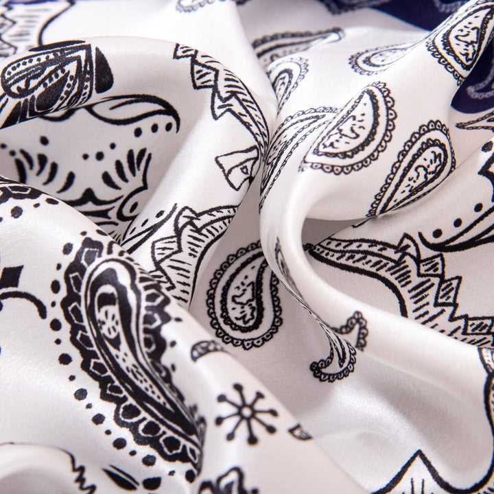 A close-up view of the Paisley Square Silk Scarf from SusanSilk, featuring a black and white paisley pattern. The material appears soft and smooth, true to the luxurious feel of SusanSilk products.