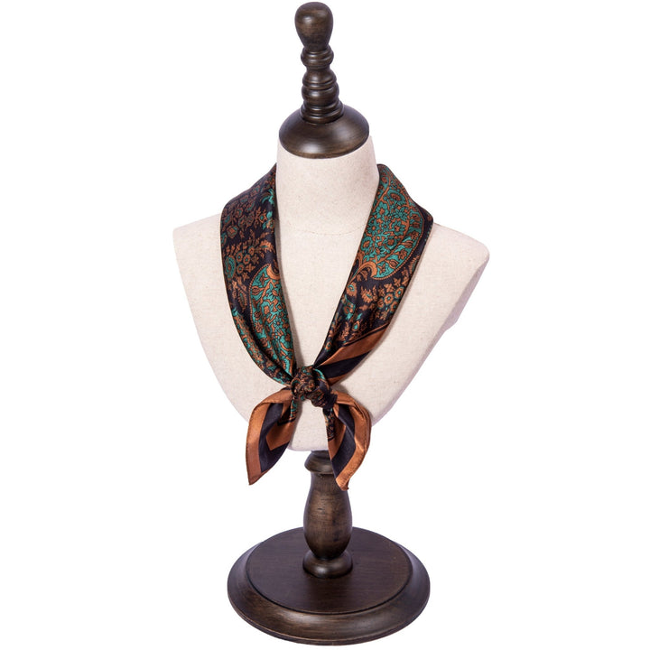 A mannequin bust displaying the Paisley Square Silk Scarf - Retro by SusanSilk, featuring green and brown patterns, tied in a knot at the front.