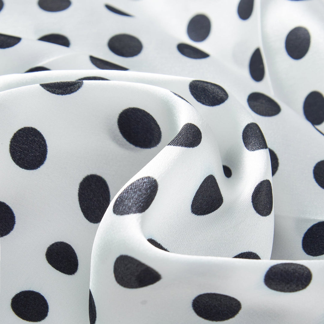 Close-up of a SusanSilk Polka Dot Square Silk Scarf, featuring white silk fabric with black polka dots, highlighting the elegant folds and wrinkles in the material.