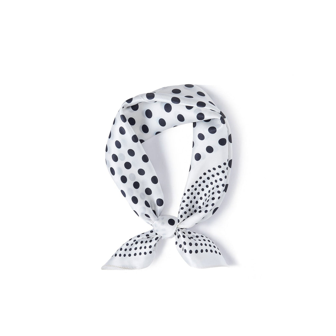 The Polka Dot Square Silk Scarf by SusanSilk, featuring a white silk fabric adorned with black polka dots, was tied in a loop with a small knot at the bottom.