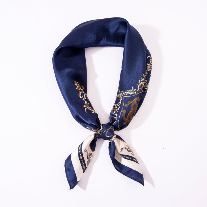 Sure, here is a rephrased version of the sentence using the given product data:

A neatly folded Royal Pattern Square Silk Scarf by SusanSilk, featuring blue and white fabric with gold decorative patterns, forming a loop with the ends tied together on a white background.