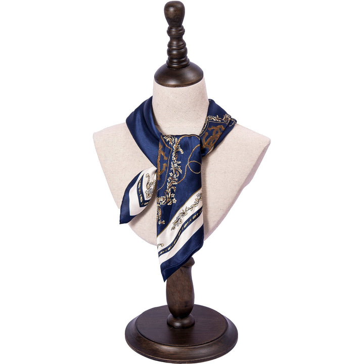 A SusanSilk mannequin torso draped with a Royal Pattern Square Silk Scarf featuring intricate gold patterns in navy blue and white, placed on a wooden stand.