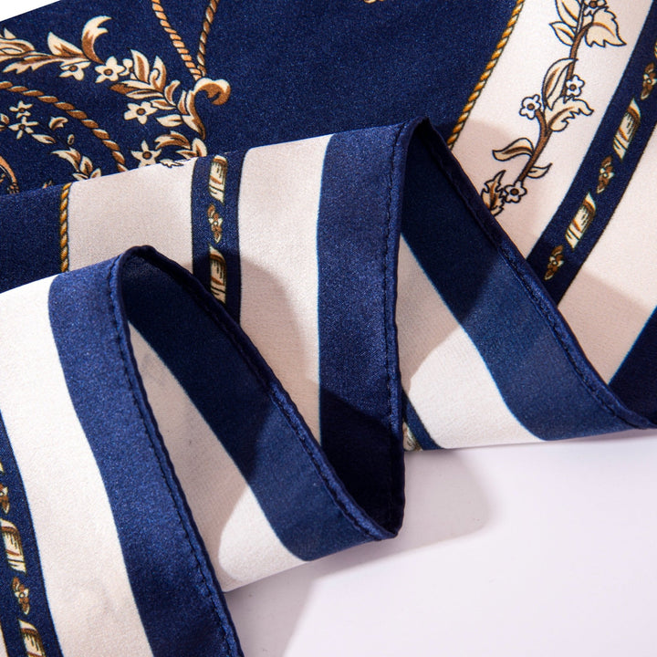 A close-up of the Royal Pattern Square Silk Scarf by SusanSilk showcases a navy blue and white striped pattern with intricate golden details.