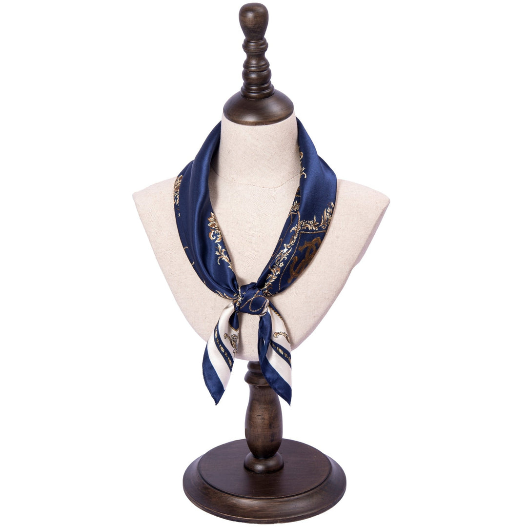 Mannequin bust showcasing a SusanSilk Royal Pattern Square Silk Scarf, featuring a navy blue and white design with a gold chain pattern.