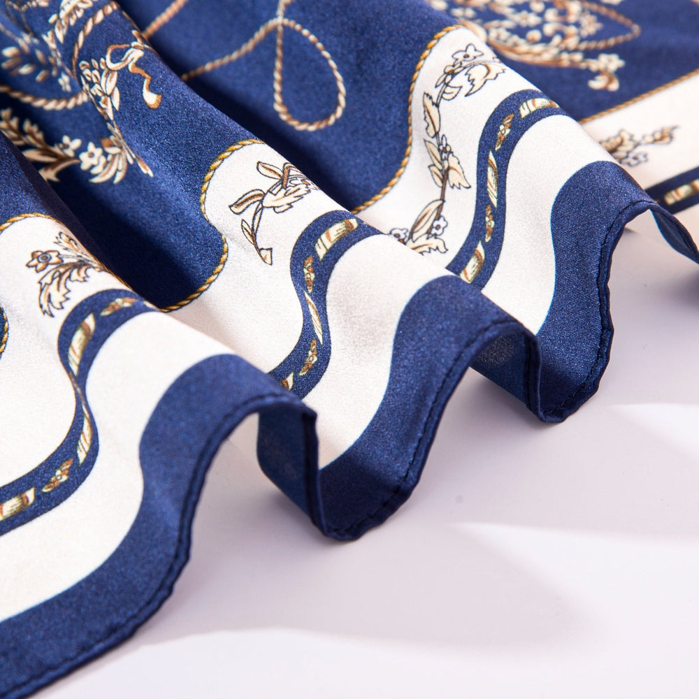 Close-up of the Royal Pattern Square Silk Scarf by SusanSilk, featuring blue and white silk fabric with intricate gold patterns, showcasing the wavy edge detail, laid flat on a white surface.